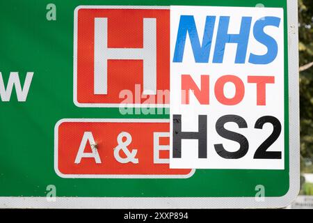 A413 Stoke Mandeville panneau de bord de route pour l'hôpital Stoke Mandeville et le stade avec panneau anti HS2 attaché. Le signe anti HS2 indique NHS et non HS2. Celui qui a produit le signe NHS NOT HS2 croyait probablement que l'argent dépensé pour HS2 devrait être utilisé pour soutenir le NHS. À quelques kilomètres de là, à la périphérie d'Aylesbury, l'A418 commence sa deuxième semaine de fermeture HS2, provoquant un ressentiment extrême des résidents locaux, des retards dans la circulation commerciale et un déroutement, ainsi que des pertes d'affaires locales. Crédit : Stephen Bell/Alamy Banque D'Images