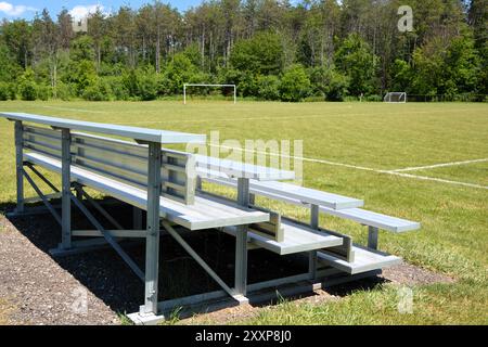 Les gradins en aluminium sont assis vides sur un terrain de football et de sport par une journée d'été ensoleillée. Banque D'Images