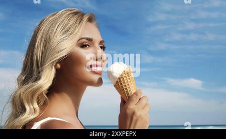 Une femme blonde aime manger une glace dans un cône Banque D'Images
