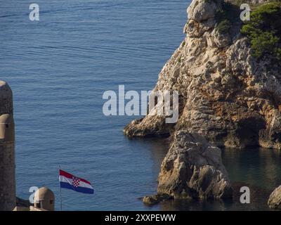 Rochers sur la côte avec un drapeau croate au premier plan et la mer en arrière-plan, Dubrovnik, mer Méditerranée, Croatie, Europe Banque D'Images