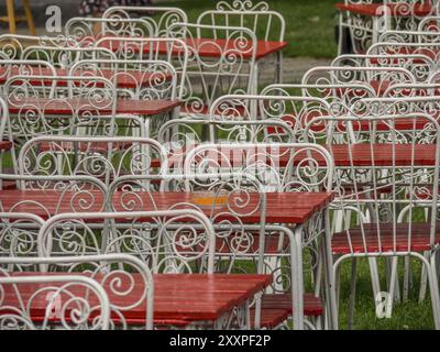 Tables et chaises en métal peintes en blanc avec des sièges et des dessus de table rouges, debout dans un motif sur une pelouse verte, ystad, suède, mer baltique, scandinavie Banque D'Images