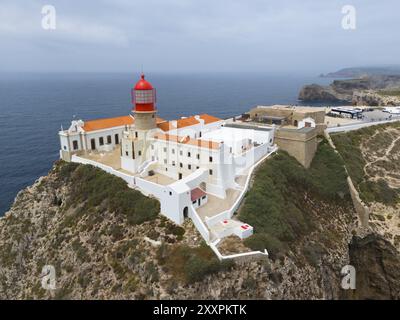 Un phare rouge sur une falaise rocheuse, entouré de bâtiments blancs, surplombant l'océan, vue aérienne, phare, Cabo de Sao Vicente, Cap St Vincen Banque D'Images