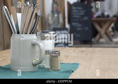 Des couverts dans une tasse de bière sur une table en bois Banque D'Images