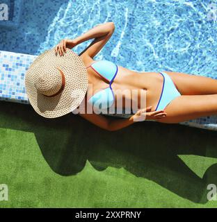 Femme au chapeau de paille vous détendre à la piscine, vue d'en haut Banque D'Images