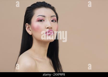Portrait of attractive young asian woman with bright représentent plus de fond beige Banque D'Images