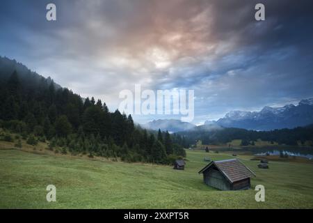 Lever de soleil brumeux au-dessus des cabanes près du lac Geroldsee dans les Alpes bavaroises, Allemagne, Europe Banque D'Images