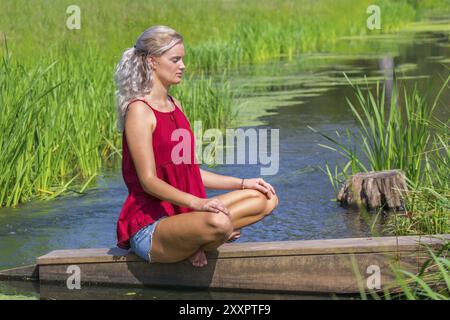 Les jeunes libre médite sur river dans la nature Banque D'Images