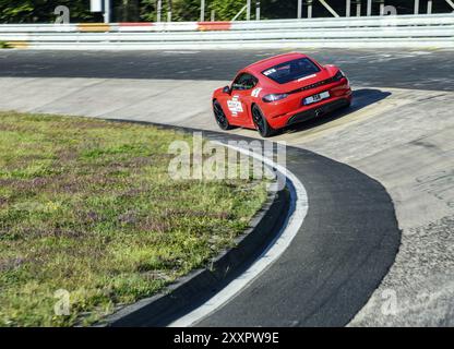 Vue du point de vue d'un pilote de course sur une voiture de sport rouge Porsche Cayman de nuerburgring.de conduisant à travers la Caracciola-Karrussell Caracci Banque D'Images