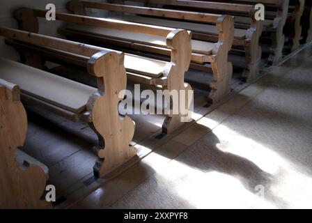 Vieux bancs en bois dans une église bavaroise avec la lumière une ombre Banque D'Images