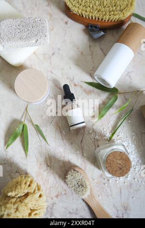 Crème visage, sérum, lotion, hydratant et sel de mer parmi les feuilles de bambou dans le bain Banque D'Images