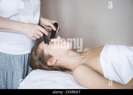 Jeune femme ont face à un traitement guasha asian beauty clinic Banque D'Images