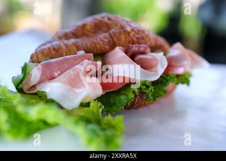 La personne met jambon sur le pain de croissant coupé en deux pour la nourriture du petit déjeuner. gros plan au ralenti Banque D'Images