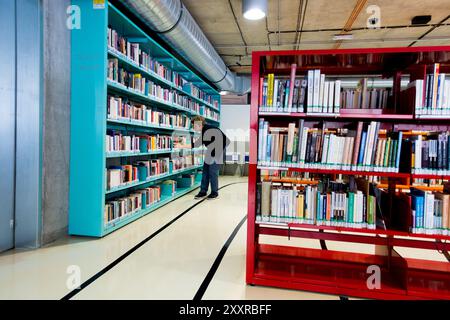 Une personne choisit des livres sur une étagère dans une bibliothèque Banque D'Images