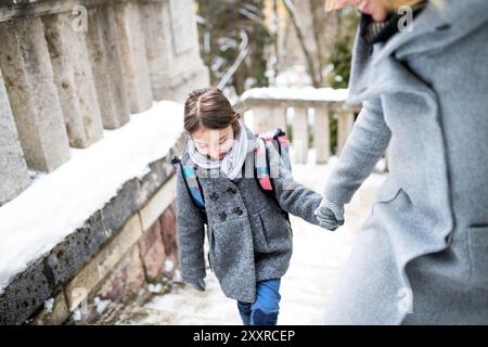 Mère emmenant sa fille à l'école, disant au revoir devant le bâtiment de l'école, se dirigeant vers le travail. Concept d'équilibre entre vie professionnelle et vie privée pour les femmes. Banque D'Images