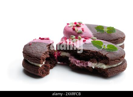 Biscuits au chocolat à la crème et glaçage rose isolés sur blanc Banque D'Images