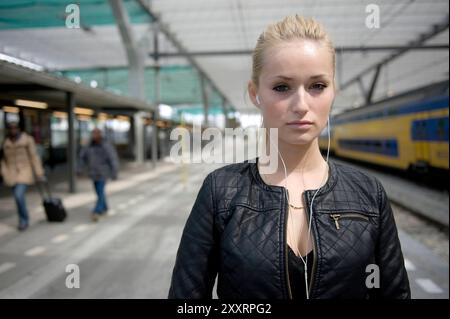 Jeune adulte, femme blonde sur la gare centrale. Younf adulte, femme blonde sur la gare centrale attendant son train Intercity & Fyra vers sa destination. Rotterdam, pays-Bas. MRYES Rotterdam Centraal Station Zuid-Holland Nederland Copyright : xGuidoxKoppesxPhotox Banque D'Images