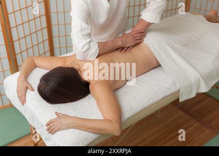 thérapeute effectue un massage shiatsu sur le dos d'une femme sur une table de massage Banque D'Images
