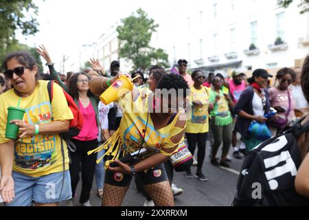 Londres, Royaume-Uni, 25 août 2024. Carnaval annuel des enfants le dimanche jour férié. Des centaines de milliers de personnes viennent à Notting Hill pour célébrer la nourriture, les boissons et la culture des Caraïbes pleines de couleurs et de costumes colorés. Les femmes du syndicat Unison dansent sur de la musique forte portant un T-shirt qui dit aimer la musique, détester le racisme. Crédit : Martin Suker/Alamy Live News Banque D'Images