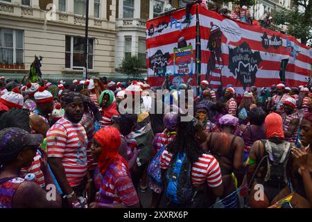 Londres, Royaume-Uni. 25 août 2024. Les fêtards habillés en personnage de livre de puzzle pour enfants Wally pulvérisent de la peinture colorée et de la poudre sur eux-mêmes et sur les spectateurs le premier jour du carnaval de Notting Hill. Crédit : Vuk Valcic/Alamy Live News Banque D'Images