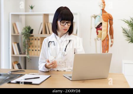 Médecin féminin examinant le flacon de médicament dans le bureau moderne Banque D'Images