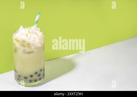 Thé à bulles vert matcha boba avec perle de tapioca. Boisson glacée froide asiatique tendance avec boules de tapioca foncées et crème fouettée non laitière, espace copie Banque D'Images