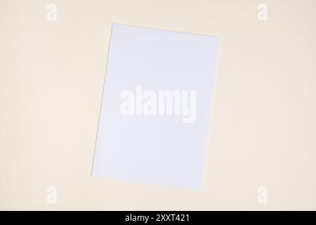Feuille de papier vierge sur fond beige, vue de dessus, espace pour le texte Banque D'Images
