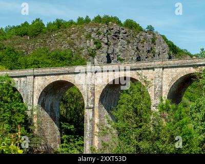 Clecy, Normandie, France, 10 mai 2024. Viaduc ferroviaire en pierre sur fond de montagne dans la ville de Cleacy en Normandie, roches gre Banque D'Images