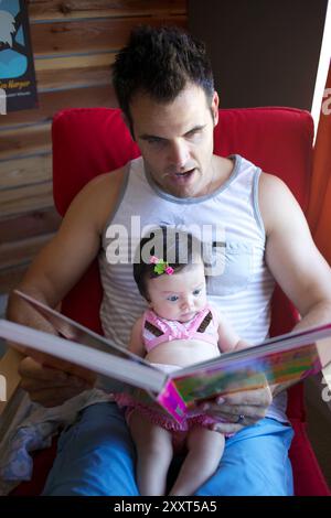 L'homme lit à Infant Daughter Banque D'Images