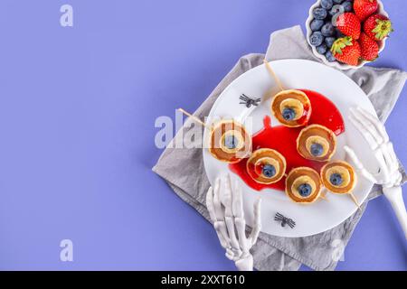 Petit déjeuner drôle pour les enfants pour Halloween. Crêpes sucrées maison créatives sous forme de monstres et symboles traditionnels d'Halloween, avec baies fraîches, chocolat Banque D'Images