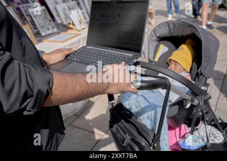 Père travaillant sur ordinateur portable tout en prenant soin de dormir bébé dehors. Télétravailleur Banque D'Images