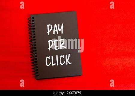 Payez par message de clic écrit sur la page de carnet noir avec fond rouge. Symbole conceptuel de paiement par clic PPC. Copier l'espace. Banque D'Images