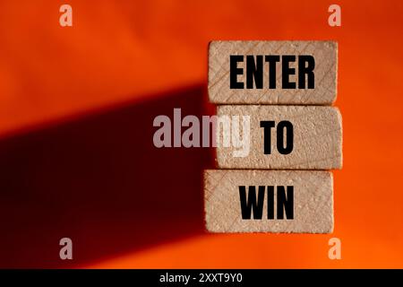 Participez pour gagner un message écrit sur des blocs de bois avec fond orange Banque D'Images