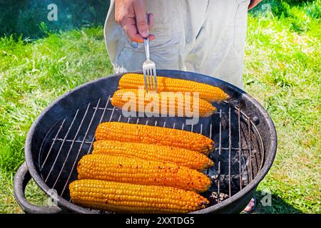 cuisson du maïs sucré sur le gril sur un barbecue par une journée ensoleillée. Nourriture végétalienne saine Banque D'Images