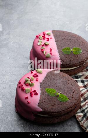 Biscuits au chocolat avec crème et glaçage rose sur fond gris Banque D'Images