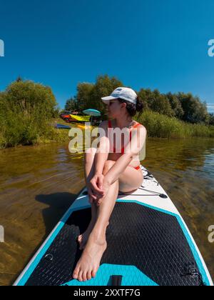 Femme heureuse se relaxant sur un Paddleboard au soleil Banque D'Images