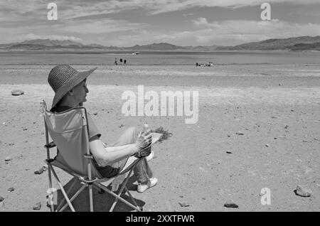 Femme caucasienne, 55 à 60 ans, assise sur une chaise et regardant la vue panoramique du lac Mead dans le Nevada, États-Unis. Banque D'Images