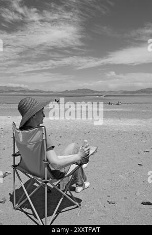 Femme caucasienne, 55 à 60 ans, assise sur une chaise et regardant la vue panoramique du lac Mead dans le Nevada, États-Unis. Banque D'Images