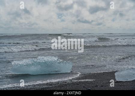 Morceaux de glace et icebergs cassés sur une plage volcanique de sable noir à Diamond Beach en Islande Banque D'Images