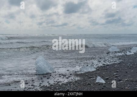 Morceaux de glace et icebergs cassés sur une plage volcanique de sable noir à Diamond Beach en Islande Banque D'Images