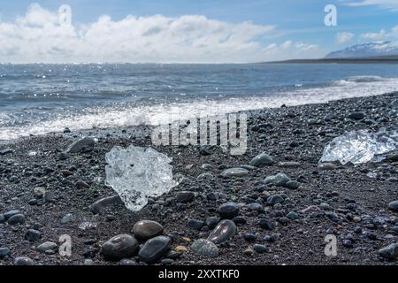 Morceaux de glace et icebergs cassés sur une plage volcanique de sable noir à Diamond Beach en Islande Banque D'Images