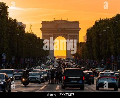 Paris, France - 10 août 2024 : circulation animée et foule au carrefour des champs-Élysées avec Arc de Triomphe au coucher du soleil Banque D'Images
