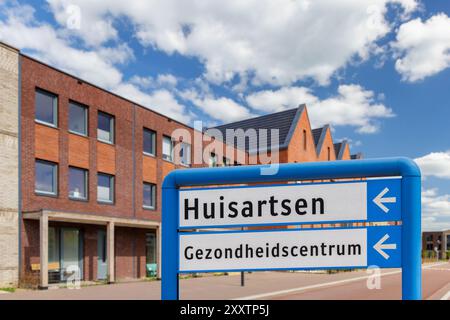Panneau d'itinéraire avec le texte néerlandais pour «médecins de famille et centre de santé» dans un quartier résidentiel avec de nouvelles maisons Banque D'Images