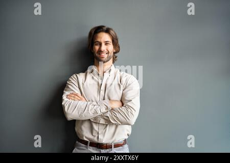 Heureux jeune homme d'affaires regardant la caméra isolé sur fond gris, portrait. Banque D'Images