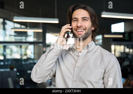 Heureux jeune homme d'affaires européen faisant appel en parlant au téléphone. Banque D'Images
