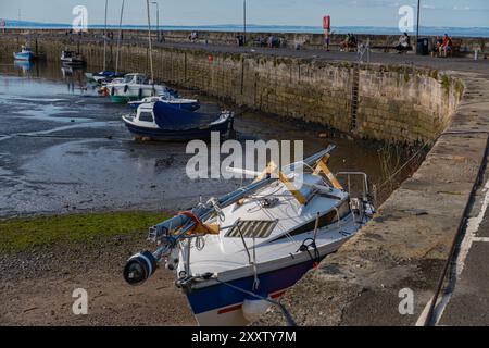 ÉDIMBOURG - 28 JUILLET 2024 : des bateaux sont ancrés à Fisherrow Harbour alors que la marée recule, révélant des vasières, avec les gens profiter de l'après-midi ensoleillé. Banque D'Images