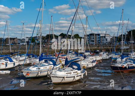 ÉDIMBOURG - 28 JUILLET 2024 : les voiliers sont ancrés et inclinés dans la boue à marée basse le long de la marina de Fisherrow Harbour, avec des bâtiments visibles à l'arrière. Banque D'Images