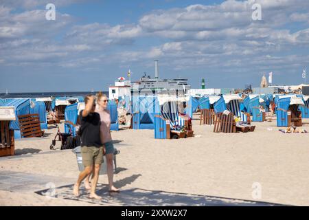 Strand von Warnemünde an der Ostsee Sommer 2024 Warnemuende, Deutschland 24. Août 2024 : eine Fähre passiert die Ostsee während Menschen einen heißen Sommertag BEI 30 Grad Celsius am Strand von Warnemünde an der Ostsee in Deutschland im Sommer 2024 genießen. Mecklembourg-Poméranie occidentale Banque D'Images