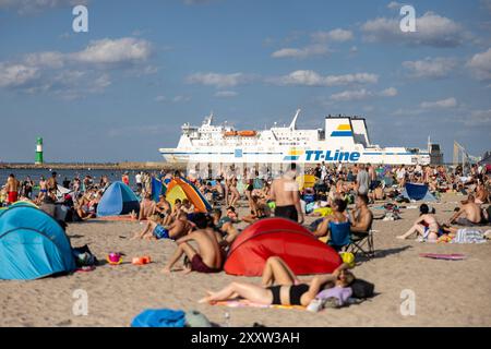 Strand von Warnemünde an der Ostsee Sommer 2024 Warnemuende, Deutschland 24. Août 2024 : eine Fähre passiert die Ostsee während Menschen einen heißen Sommertag BEI 30 Grad Celsius am Strand von Warnemünde an der Ostsee in Deutschland im Sommer 2024 genießen. Mecklembourg-Poméranie occidentale Banque D'Images