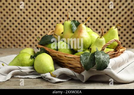 Poires vertes fraîches et feuilles avec des gouttes d'eau sur la table en bois Banque D'Images