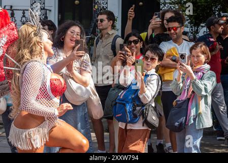 Notting Hill, Londres, Royaume-Uni. 26 août 2024. Le plus grand festival de rue d’Europe se déroule dans les rues de Notting Hill. Des danseurs exotiques et des groupes musicaux sur le thème jamaïcain défilent dans les rues, avec de la nourriture et des divertissements de rue autour de la région ajoutant à l'événement. Le Grand Parade a lieu le lundi jour férié comme point culminant du festival de trois jours, qui a commencé en 1966. Touristes regardant Banque D'Images